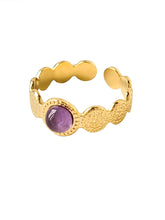 Goldener Ring mit gehämmerter Struktur, in der Mitte ist ein lila Stein
